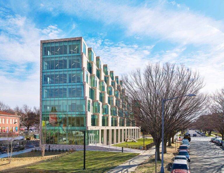 YKK modern glass office building with trees and parked cars.