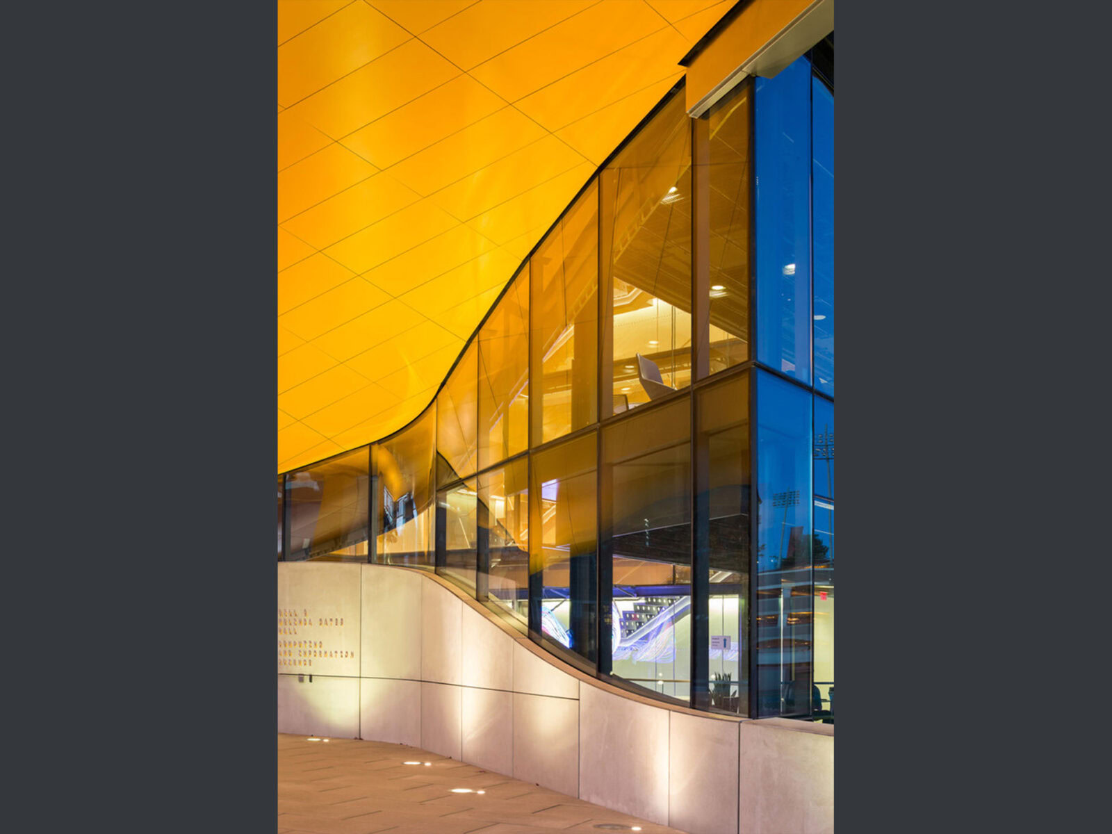 Contemporary building with large glass windows and yellow ceiling.