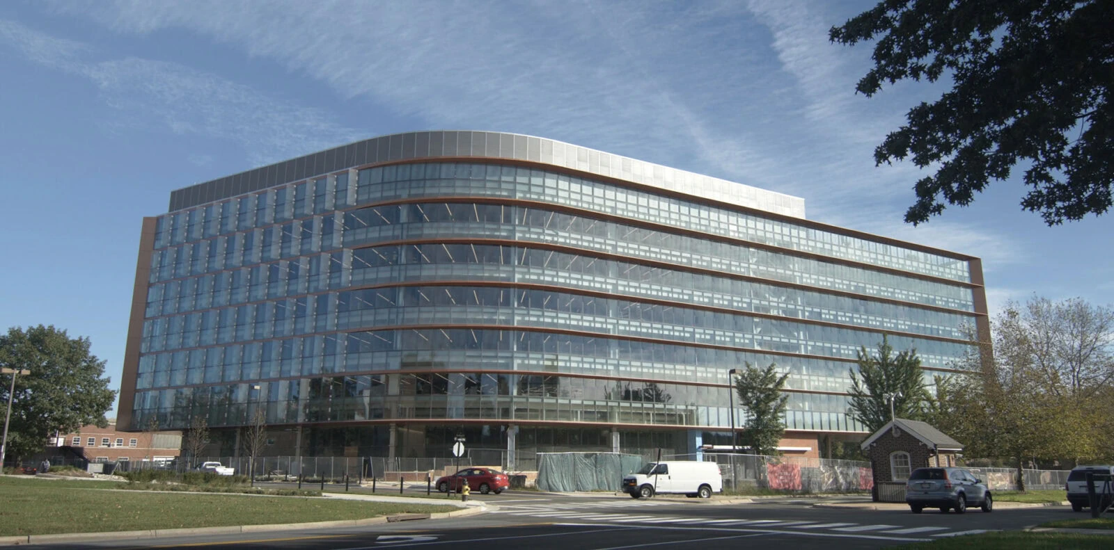 Modern glass office building with YKK branding and surrounding greenery.