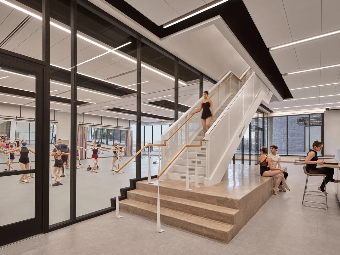 Modern indoor fitness center with glass walls and staircase, YKK windows.