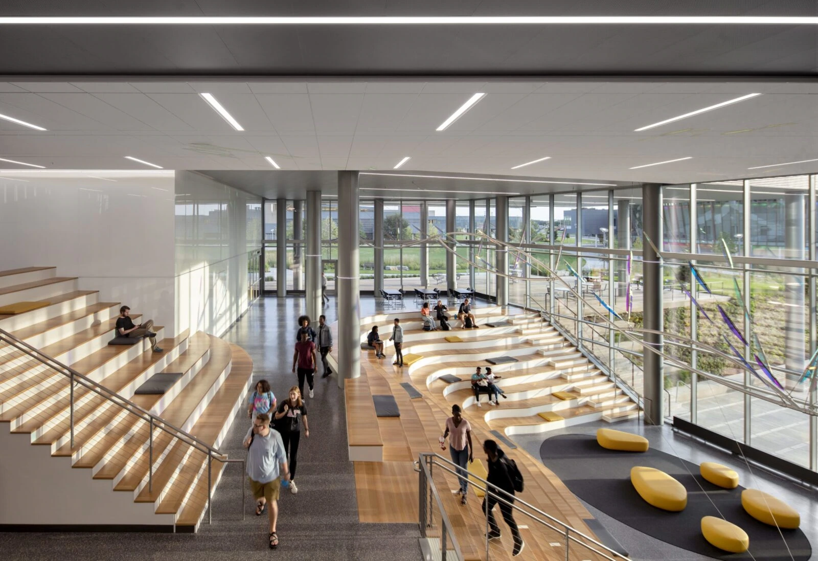 A modern, spacious lobby with glass walls and wooden seating areas.