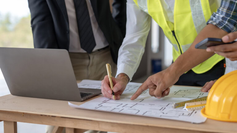 YKK construction workers reviewing blueprints and plans.