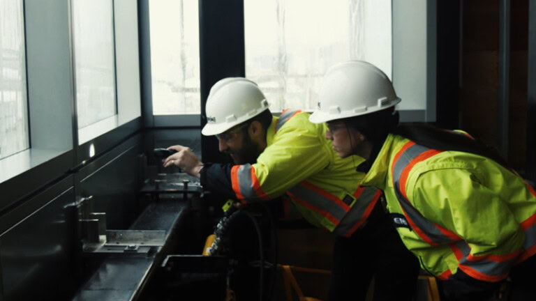 Two construction workers installing a window with YKK products.