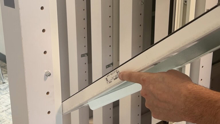 YKK window frame installation with a hand pointing at the frame in a building in.