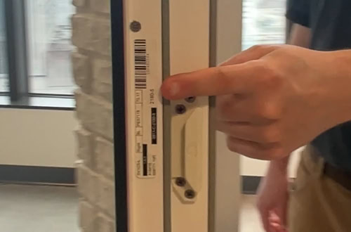 Close-up of a person installing a YKK door lock mechanism on a door frame.