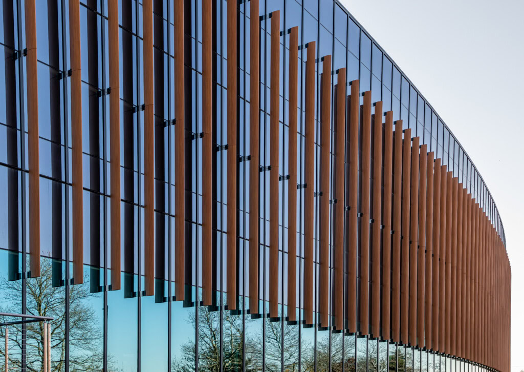 Contemporary glass building with wooden facade and reflective windows.
