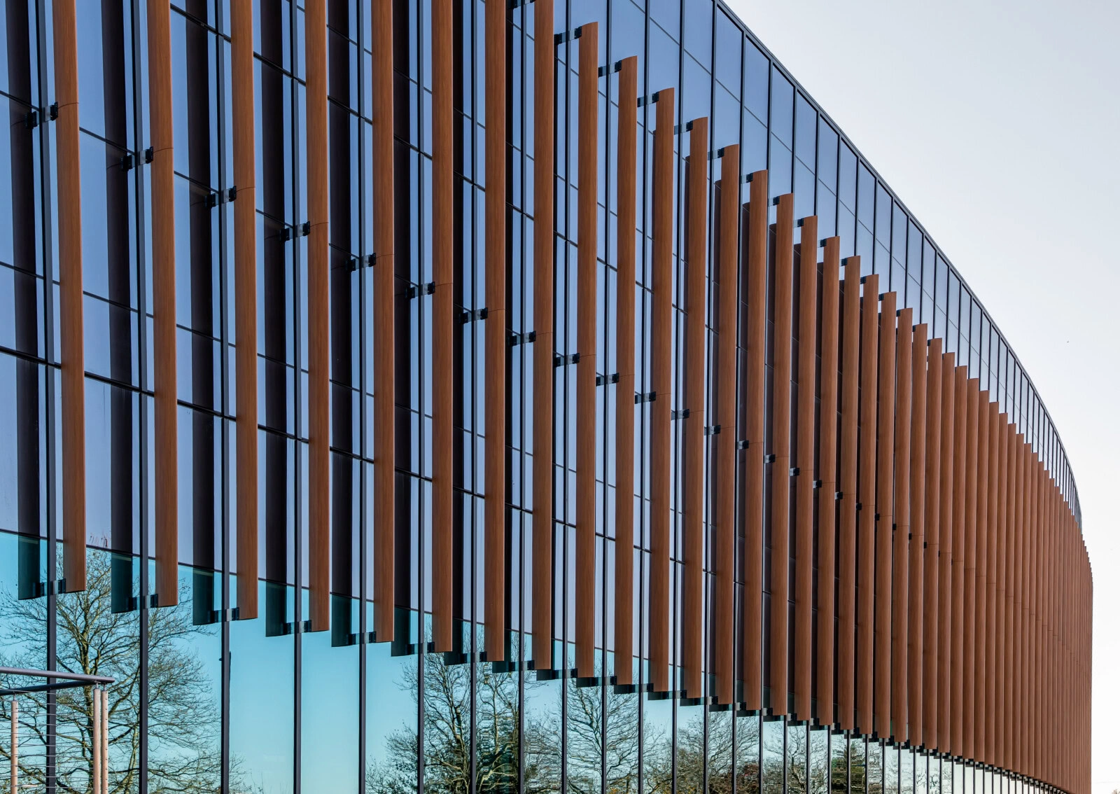 Contemporary glass building with wooden facade and reflective windows.